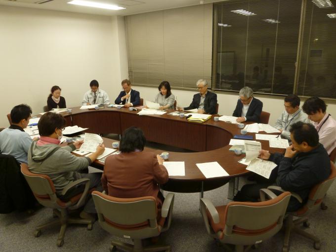12名の男女が会議室で円卓を囲んで幹事会をしている写真
