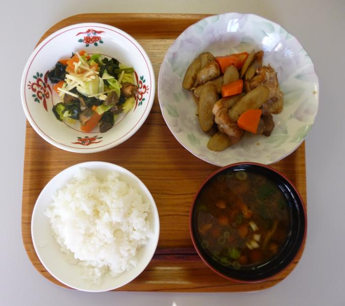 配膳された鶏肉と根菜のマーマレード煮、わかめとお漬物の酢の物、なめこ汁、白ごはんの写真