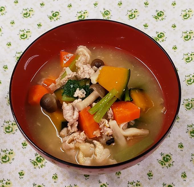 配膳された豚肉と緑黄色野菜の具だくさん味噌汁の写真