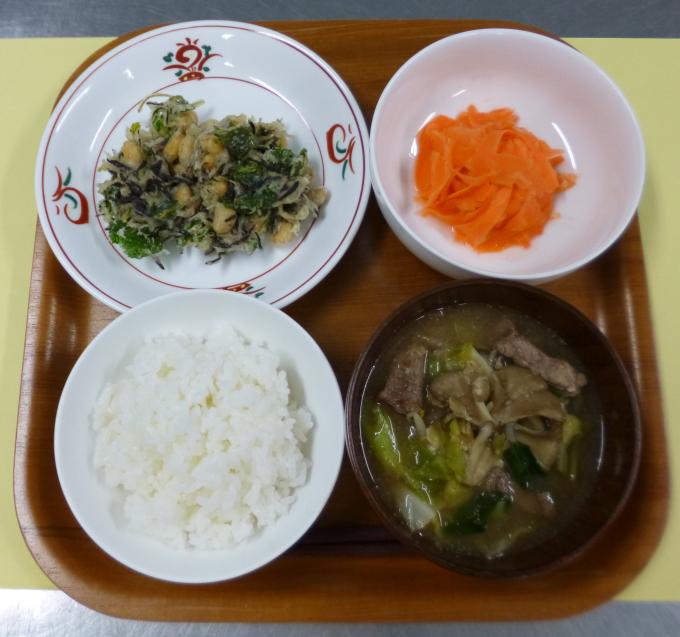 配膳されたひじきと大豆のかき揚げ、にんじんのはちみつレモン和え、豚肉とキャベツのごま味噌汁、白ごはんの写真