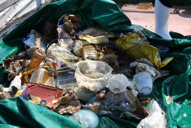 緑色のシートの上に置かれた、プラスチックなどのゴミ