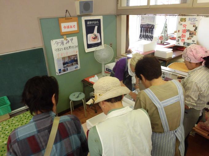 直売所で商品を選ぶ4人の後ろ姿の写真