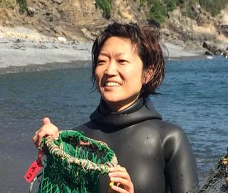 緑のネットのようなものをもって笑顔で写っている大野愛子さんの写真