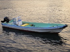 船が一艘夕日が差す水面に浮かんでいる様子の写真