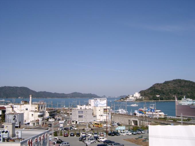 城山公園展望 、手前に建物が並びその向こうに海や山が見え海には船が航行している写真画像