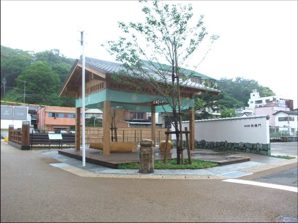 一本の木の側に東屋がある、白い塀の相橋門の写真