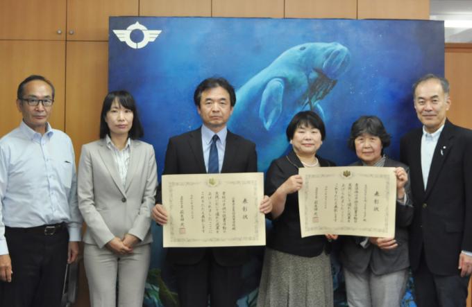 画像:鳥羽高等学校の角屋貴久校長と学校司書の加藤美貴子さんと鳥羽おはなしの会 「ミルキーウェイ」代表の鬼藤千代子さん、世古三穂子さんと中村市長と男性1名が賞状とともに写った記念写真