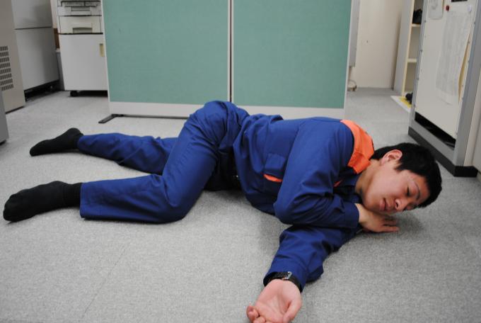 左手を下、右手を顎の下にし、横向きの体位で横たわる男性の写真