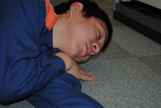 顎の下に右手を置き、口元を床に向けて横たわる男性の写真