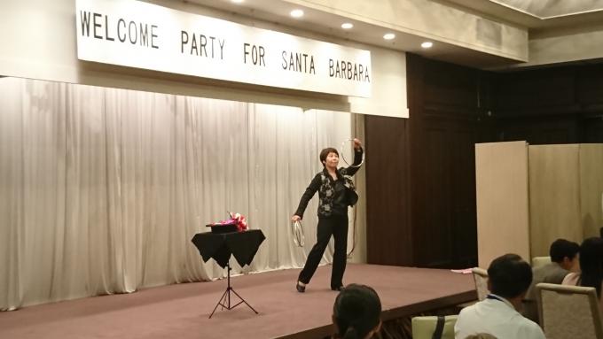 ホテルの宴会場のステージにて、マジックを披露する人の写真。