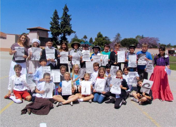 青空の下25人の小学生たちがそれぞれ絵と詩を持って並んでいる写真