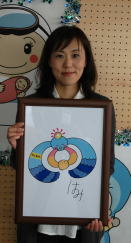 最終候補に選ばれた柴山真奈美さん自分が描いた絵を持ち、笑顔で立っている写真