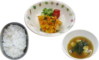 ご飯と豆腐とわかめの味噌汁、人参やトマトが入った野菜のおかずという、家庭的な献立の給食の写真