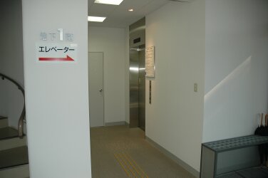 白い壁の地下1階にある、銀色のエレベーターの入り口の写真