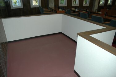 薄いピンクの床と白い囲いで出来た、車椅子用傍聴席の写真