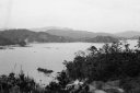 画像：奥には山々があり、手前には木々が生い茂っていて、その間には海が写っている白黒の写真
