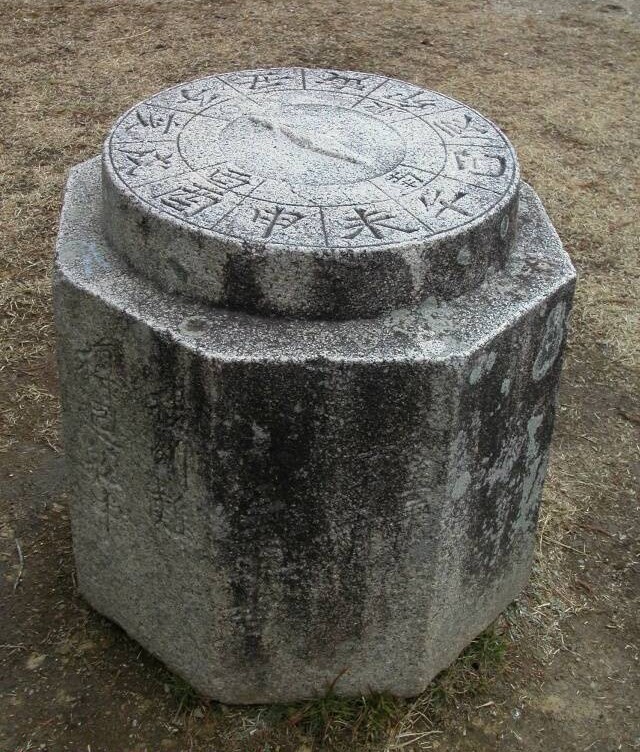 石でできた八角柱の上に円盤の方位盤を乗せたかたちをしている日和山の方位石の写真画像