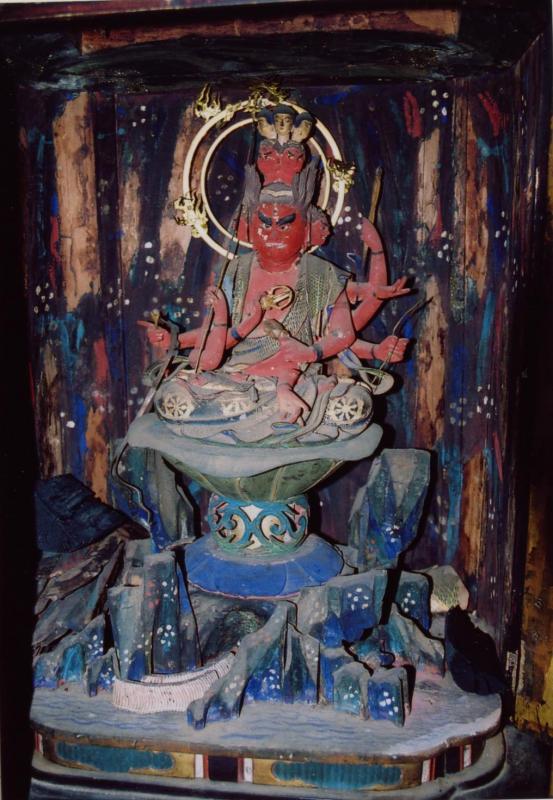 八つの手を持つ赤い身体の仏が緑青色の台座に座っている木造三宝荒神像の写真画像