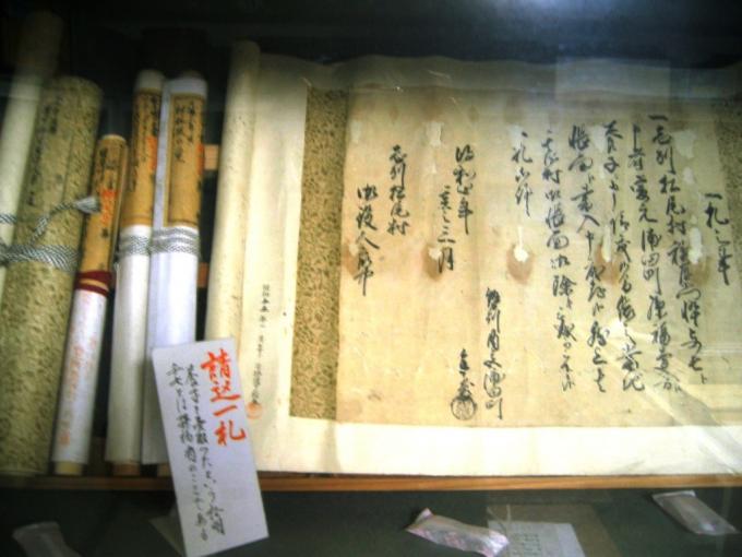 松尾村近世資料で筆のようなもので書かれた古文書と数冊の巻物の写真画像