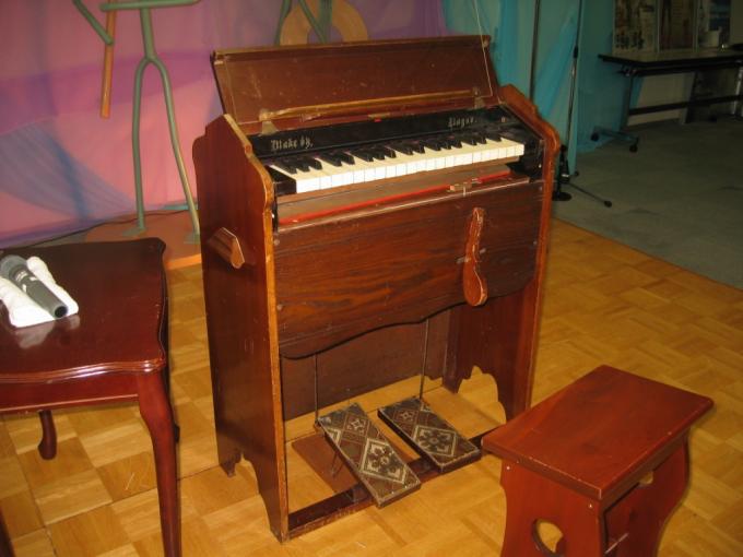 木製の椅子と二つのペダルと鍵盤がある長尾オルガンの写真画像