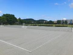 晴天の下、灰色の砂入り人工芝が特徴の鳥羽中央公園庭球場のテニスコートが一面に広がる写真