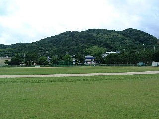 山を背に一面に広がる、芝生フィールドの写真