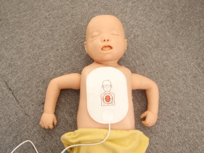 床に仰向けで横たわる上半身裸の乳児の人形に、イラスト入りのAEDの電極パッドを貼り付けた写真