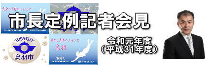 令和元年度 市長定例記者会見。市章や市長の写真、市の形状などが背景にデザインされている。